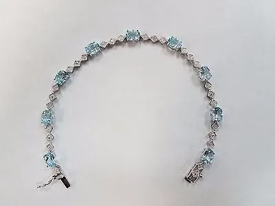 9 CARAT OVAL BLUE TOPAZ AND DIAMOND BRACELET IN RHODIUM PLATED BRASS